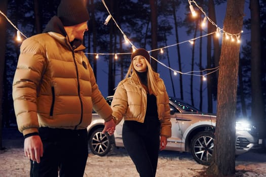 Automobile parked behind. Couple standing in the forest and celebrating New year.