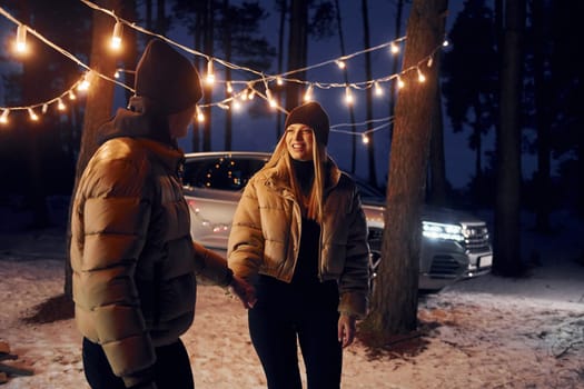 Automobile parked behind. Couple standing in the forest and celebrating New year.