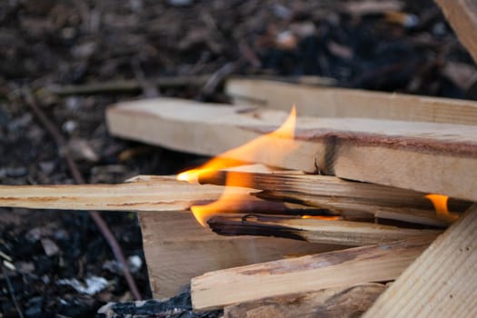 A fire burns in a campfire with a red fire in the background. High quality photo