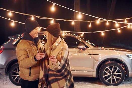 Holding sparklers. Couple standing in the forest and celebrating New year.
