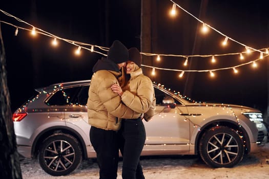 Holiday mood and decorations. Couple standing in the forest and celebrating New year.