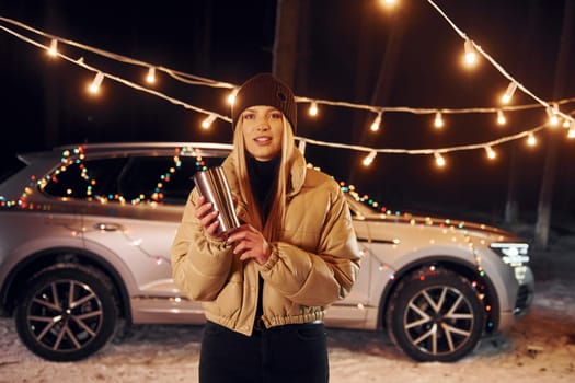 Car behind. Woman standing in the forest and celebrating New year.