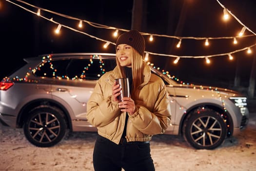 With thermos. Woman standing in the forest and celebrating New year.