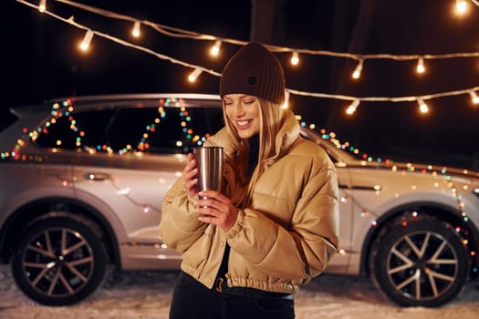 With thermos. Woman standing in the forest and celebrating New year.