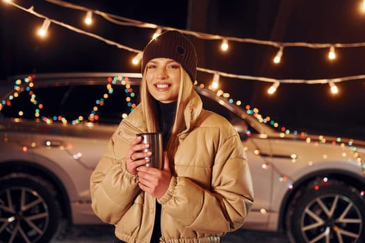 With thermos. Woman standing in the forest and celebrating New year.