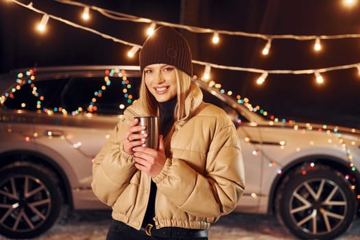 With thermos. Woman standing in the forest and celebrating New year.