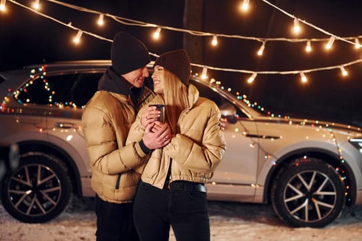 Yellow colored lighting. Couple standing in the forest and celebrating New year.