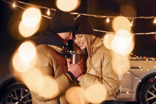 Yellow colored lighting. Couple standing in the forest and celebrating New year.