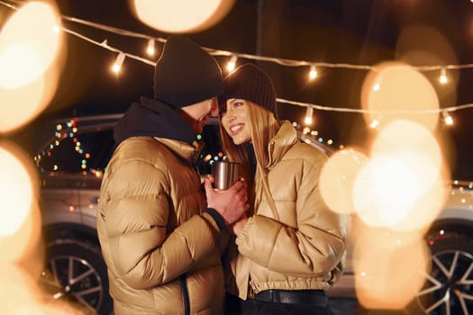 Yellow colored lighting. Couple standing in the forest and celebrating New year.
