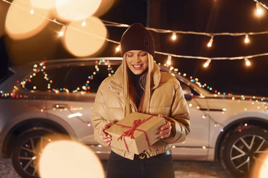 Holding gift box. Woman standing in the forest and celebrating New year.
