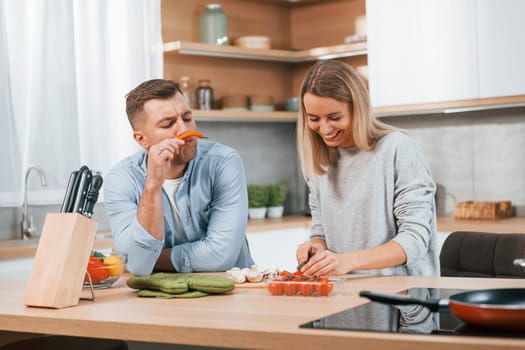 Cute people. Couple preparing food at home on the modern kitchen.