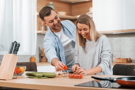 Helping each other. Couple preparing food at home on the modern kitchen.