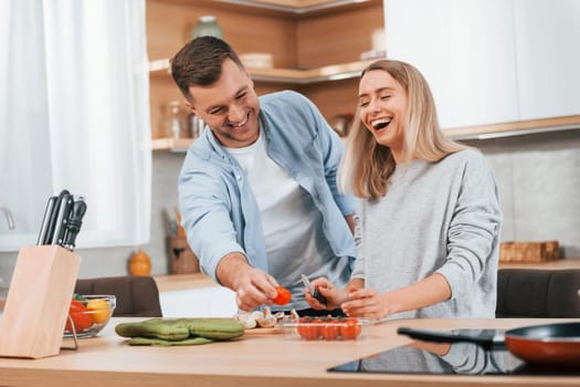 Helping each other. Couple preparing food at home on the modern kitchen.