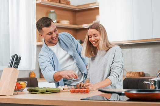 Helping each other. Couple preparing food at home on the modern kitchen.