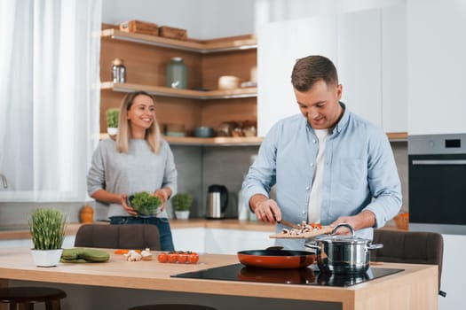 Helping each other. Couple preparing food at home on the modern kitchen.