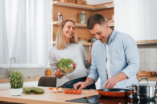 Man standing by the table. Couple preparing food at home on the modern kitchen.