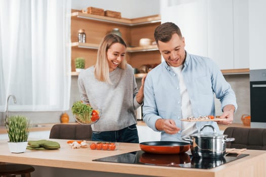 Man standing by the table. Couple preparing food at home on the modern kitchen.