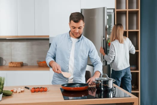 Preparing dinner. Couple at home on the modern kitchen.