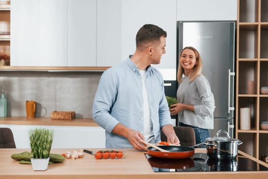 Preparing dinner. Couple at home on the modern kitchen.