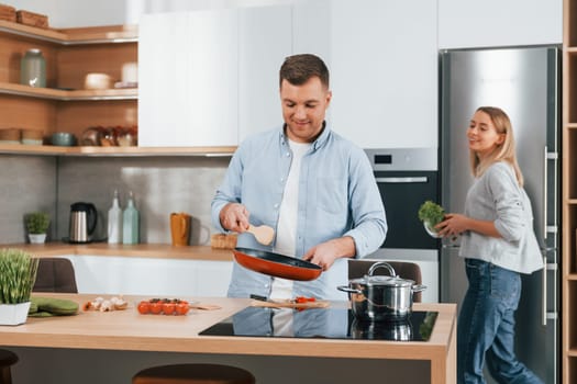 Preparing dinner. Couple at home on the modern kitchen.