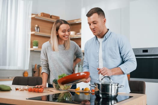 Delicious dinner. Couple preparing food at home on the modern kitchen.