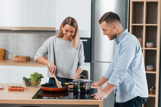 Delicious dinner. Couple preparing food at home on the modern kitchen.