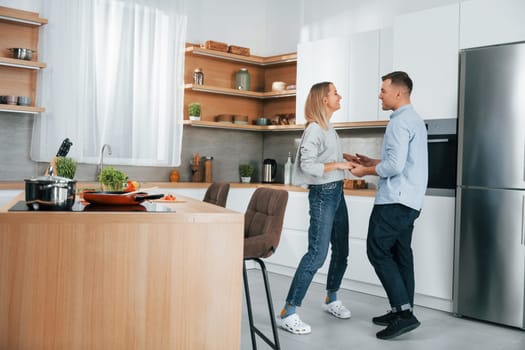 Dancing together. Couple preparing food at home on the modern kitchen.