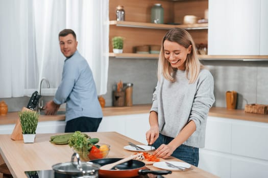 Positive emotions. Couple preparing food at home on the modern kitchen.