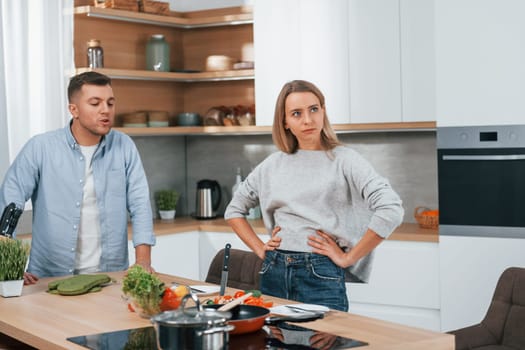 Arguing with each other. Couple preparing food at home on the modern kitchen.