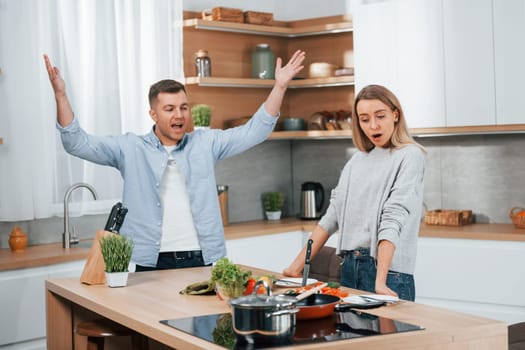 Arguing with each other. Couple preparing food at home on the modern kitchen.