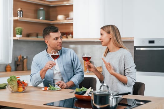 With glasses of wine. Couple preparing food at home on the modern kitchen.