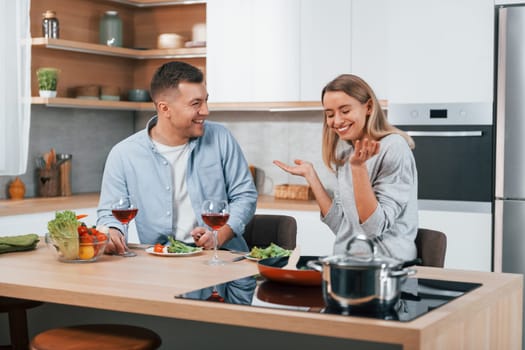 With glasses of wine. Couple preparing food at home on the modern kitchen.