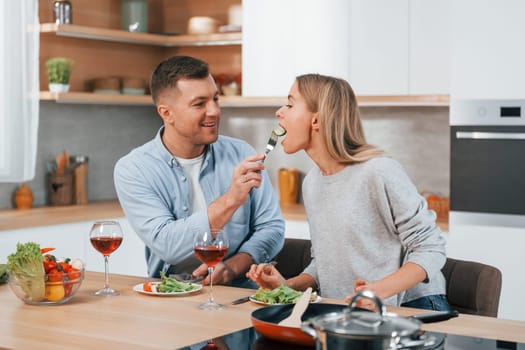 With glasses of wine. Couple preparing food at home on the modern kitchen.