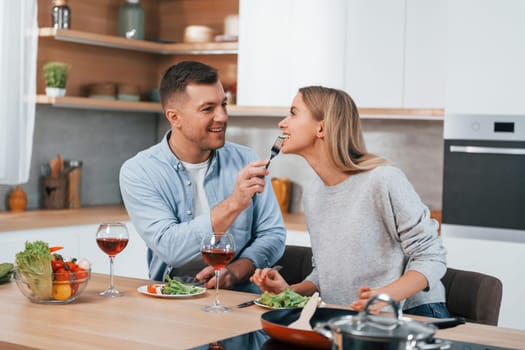 Tasting delicious food. Couple at home on the modern kitchen.