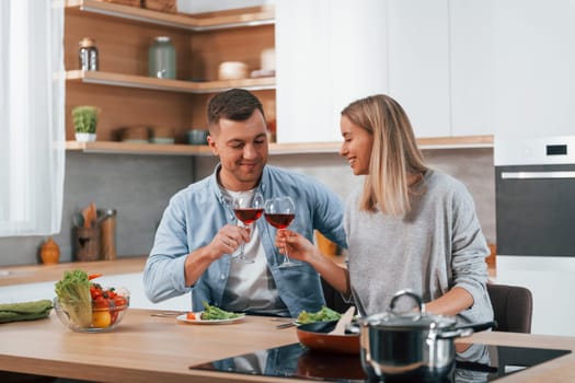 Having weekend together. Couple preparing food at home on the modern kitchen.