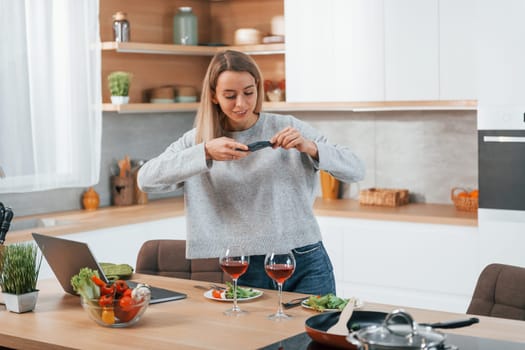 Taking pictures. Woman preparing food at home on the modern kitchen.