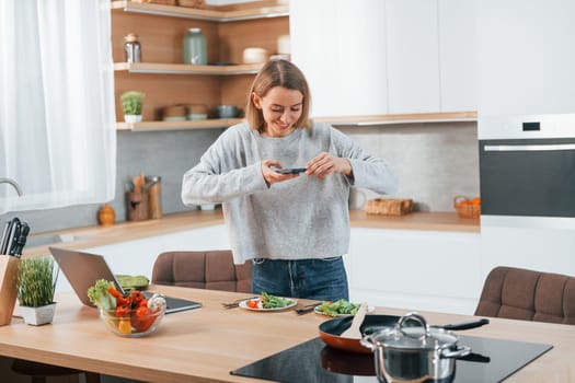 Taking pictures. Woman preparing food at home on the modern kitchen.