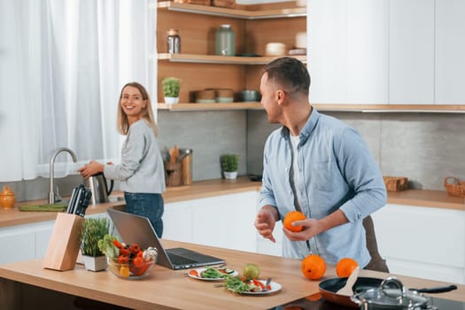 Having weekend together. Couple preparing food at home on the modern kitchen.