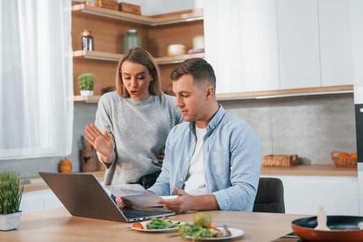 Using internet. Couple preparing food at home on the modern kitchen.