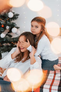 Having fun. Mother with her little daughter is having fun indoors on the bed.