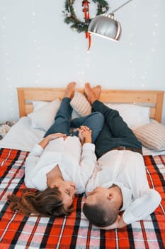 Looking at each other. Lovely couple celebrating holidays together indoors.