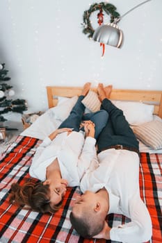 Looking at each other. Lovely couple celebrating holidays together indoors.