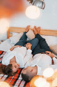 Laying down on the bed. Lovely couple celebrating holidays together indoors.