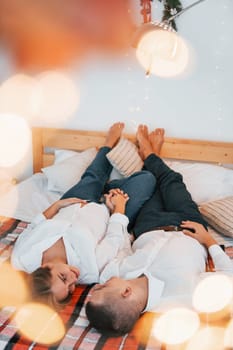 Laying down on the bed. Lovely couple celebrating holidays together indoors.