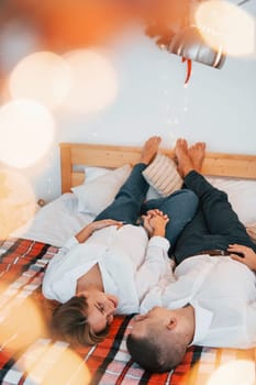 Laying down on the bed. Lovely couple celebrating holidays together indoors.