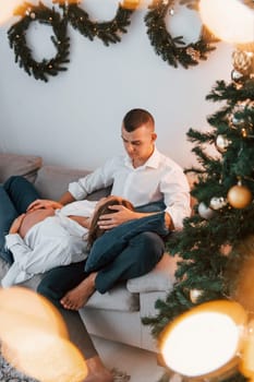 Woman is pregnant. Lovely couple celebrating holidays together indoors.