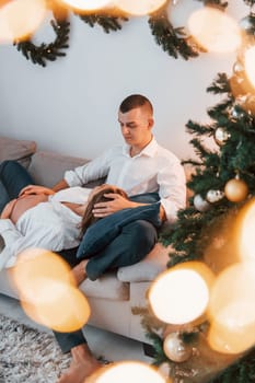 Woman is pregnant. Lovely couple celebrating holidays together indoors.