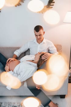 Woman is pregnant. Lovely couple celebrating holidays together indoors.