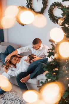 Laying down on the bed. Happy family celebrating holidays indoors together.