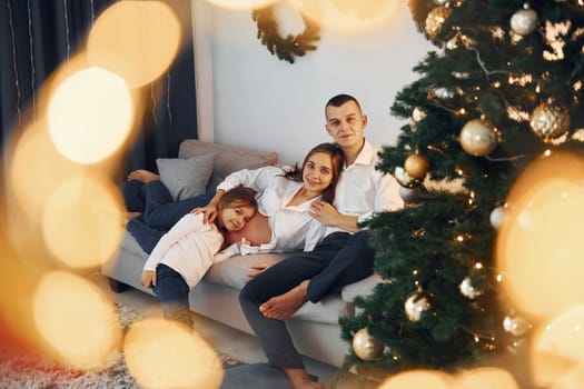 With Christmas tree. Happy family celebrating holidays indoors together.